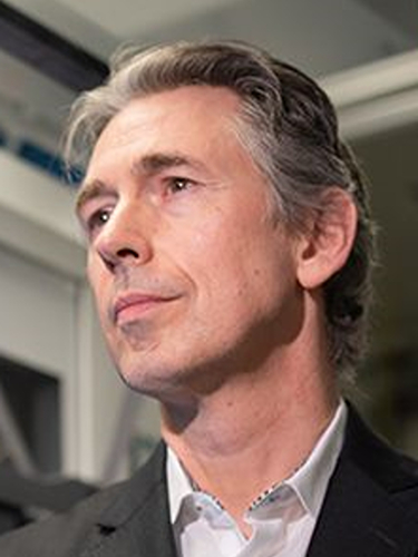 Robert Damoiseaux wearing a dark suit jacket and white button-down shirt