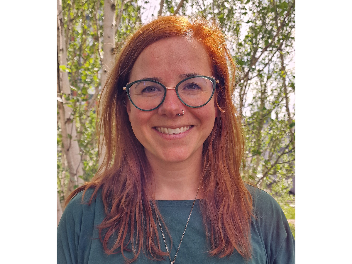 Dr Rebecca Beveridge with red hair, glasses and green top smiling to camera