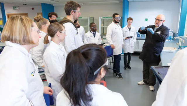 Group of young chemical scientists following demonstration in lab Group of young chemical scientists following demonstration in lab