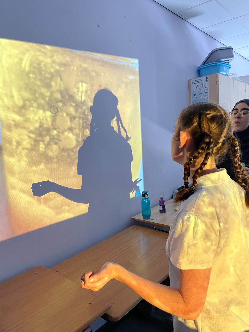 A girl looks at an image projected onto a wall