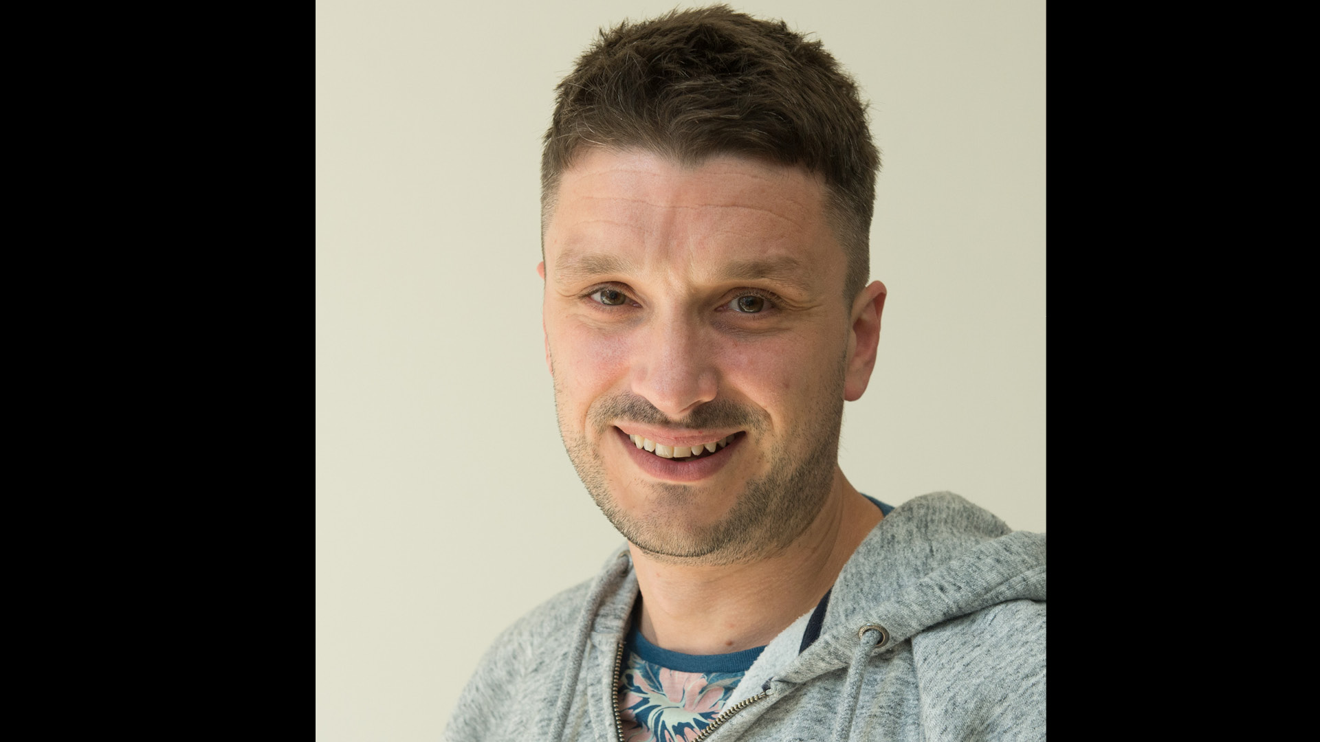 Team member Craig Early of Did You Know smiling to camera in grey hooded jumper