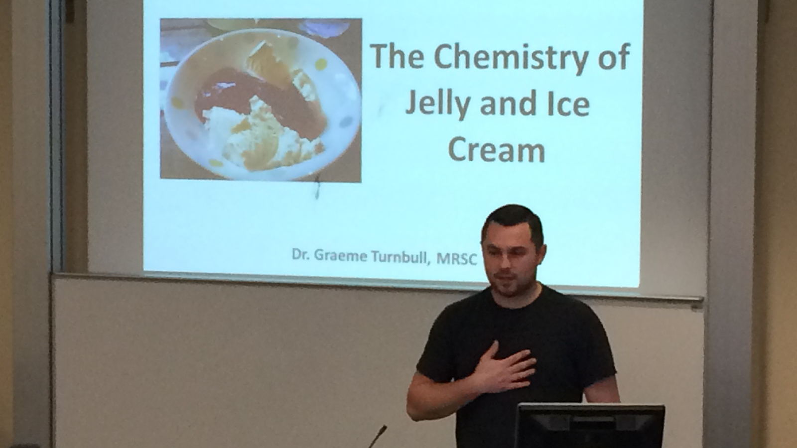 Dr Graeme Turnbull delivering presentation in front of screen