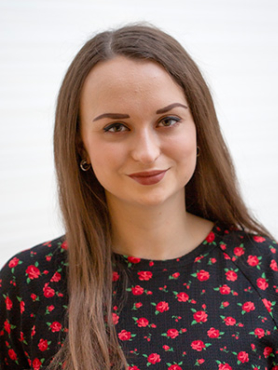 Amy Modaffar smiling to camera in black top with small red roses