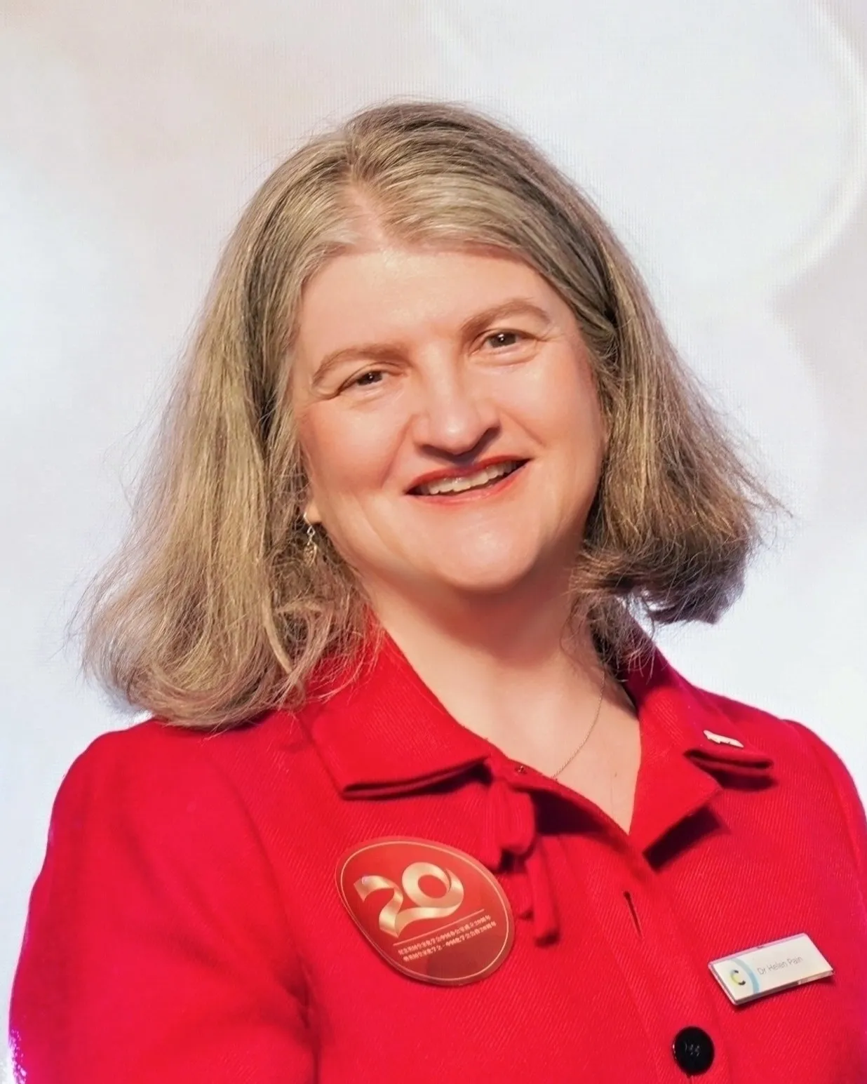 Helen Pain crop (preferred image 2026) A headshot of Dr Helen Pain smiling while wearing in a red shirt