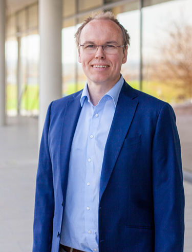 Gregor Kieslich smiling, wearing a light blue shirt and a tailored dark blue blazer