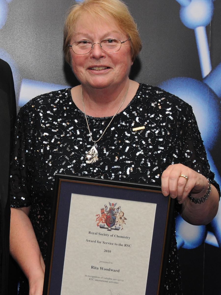 Rita smiling to camera holding recognition certificate