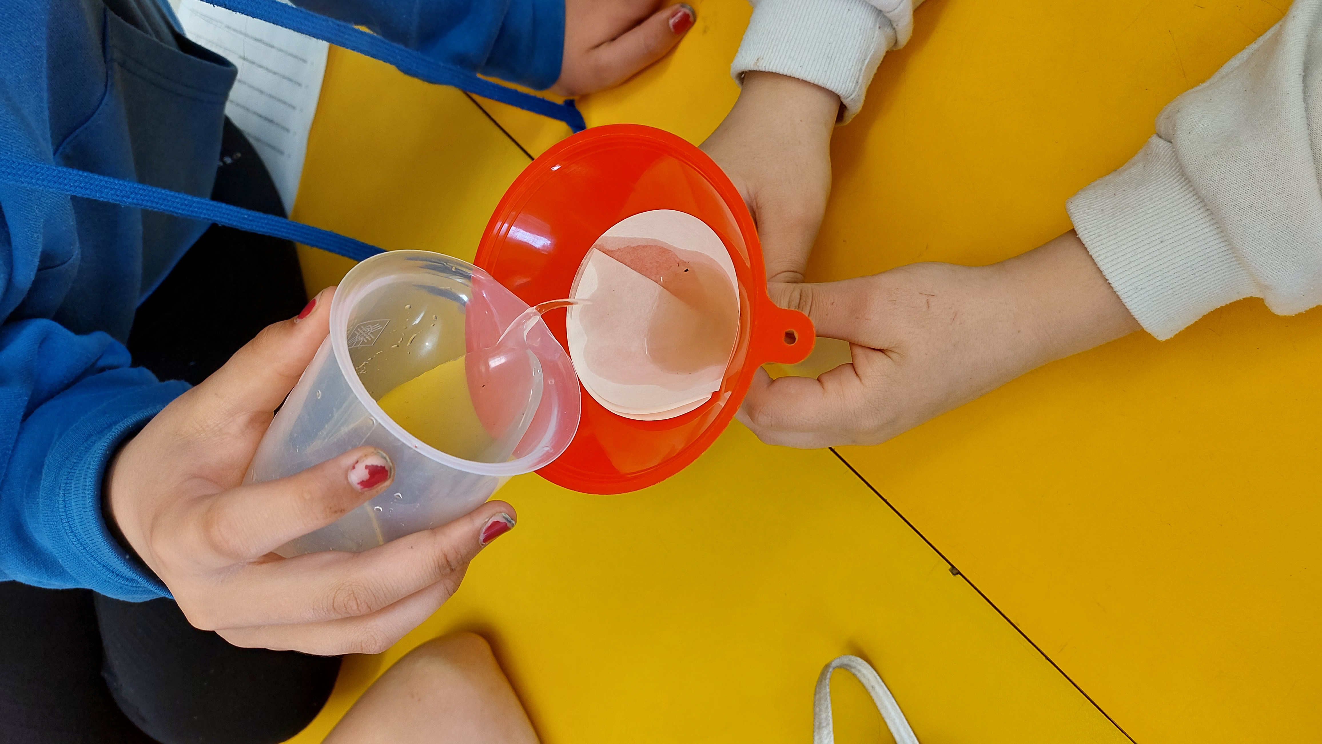 Liquid is poured from a beaker into a funnel with a lining.