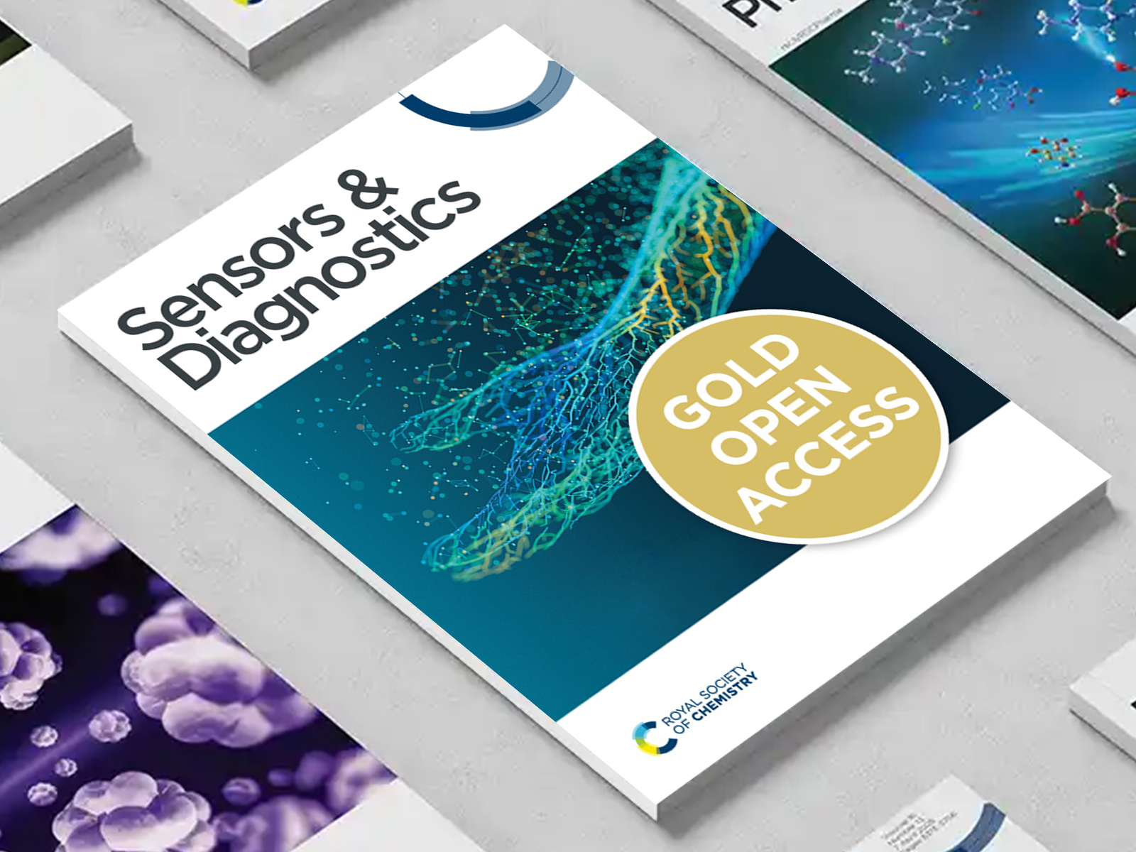 the Sensors & Diagnostics journal among a group of other journals on a desk