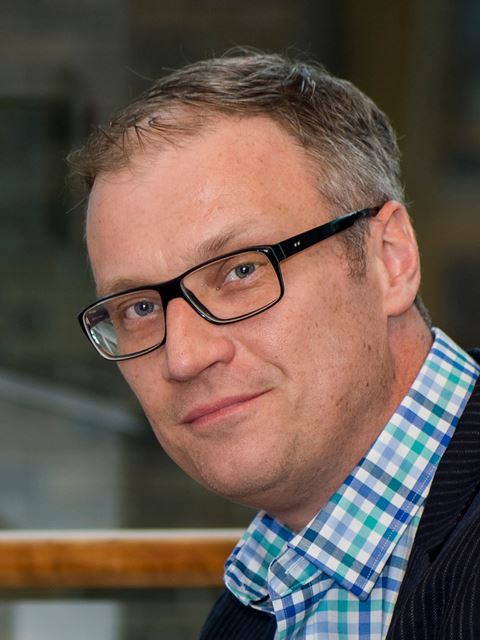Andrei Yudin wearing glasses, in blue and green small checked shirt