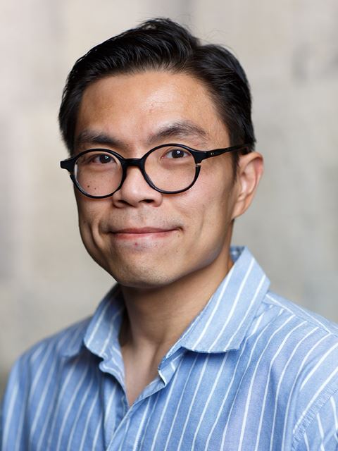Hans Renata smiling to camera in blue striped smart shirt and glasses