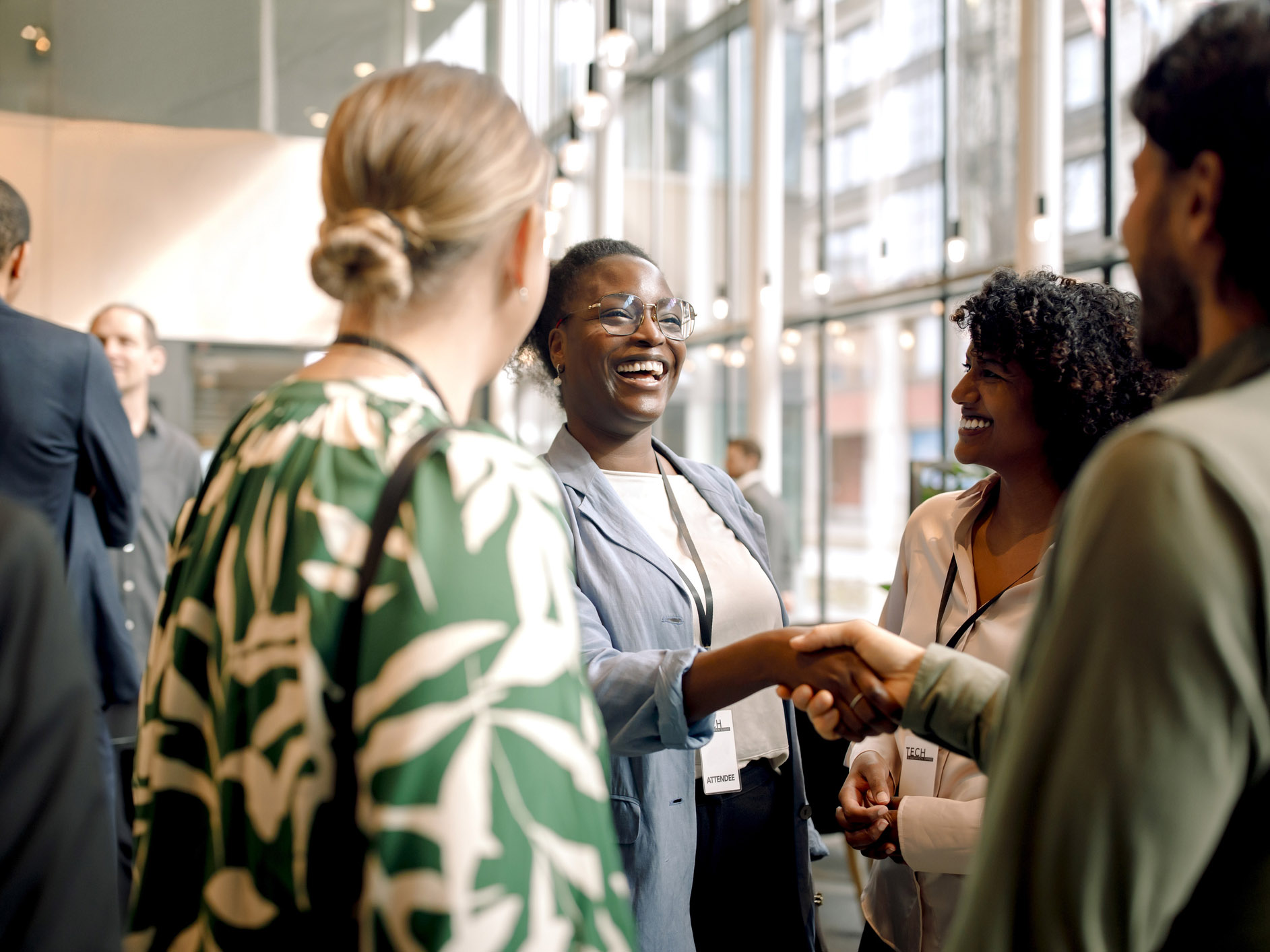 A group of smiling professionals smiling and shaking hands at a conference