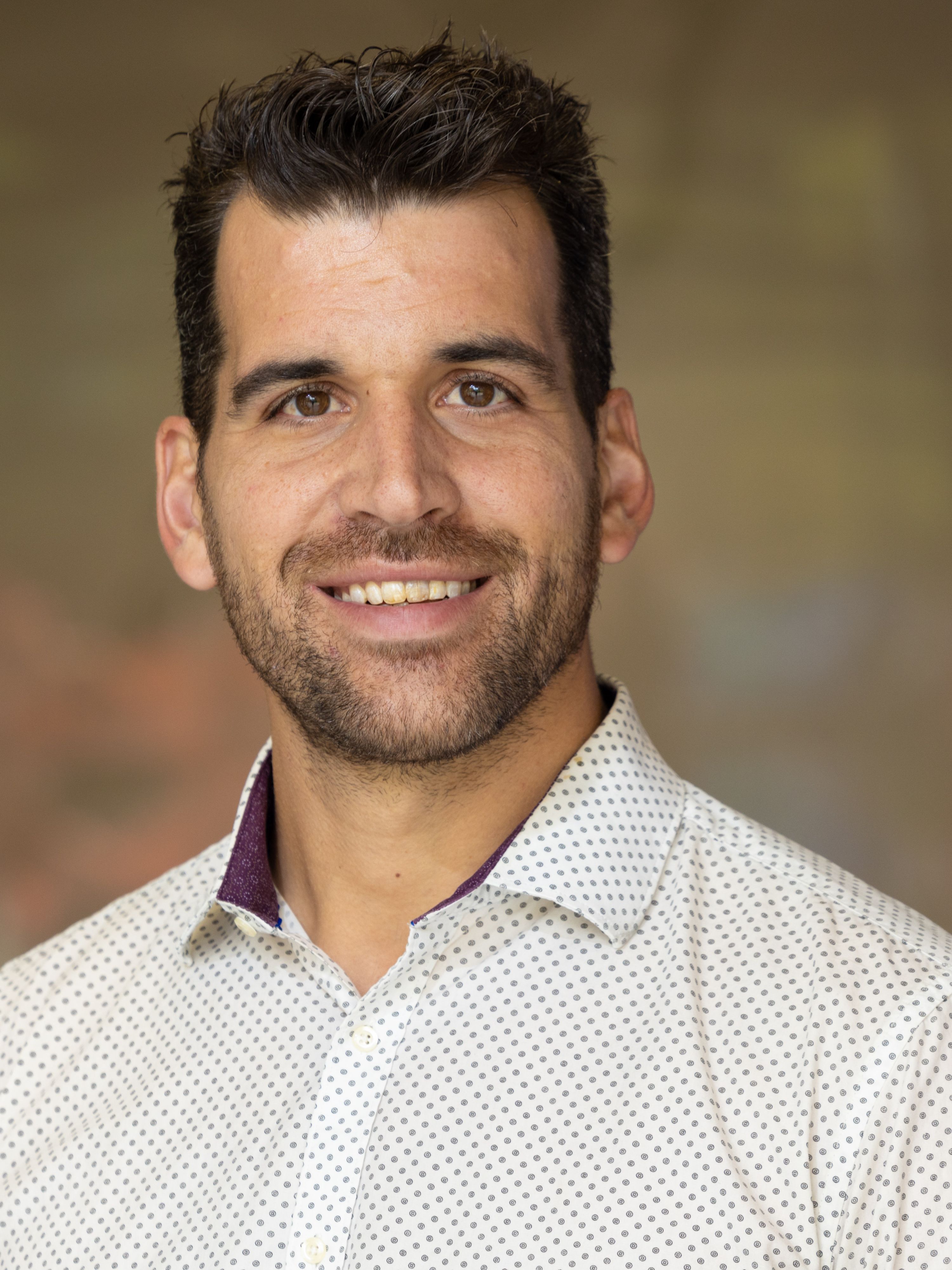 Frank Leibfarth with beard and moustache, smiling to camera in spotted white shirt.