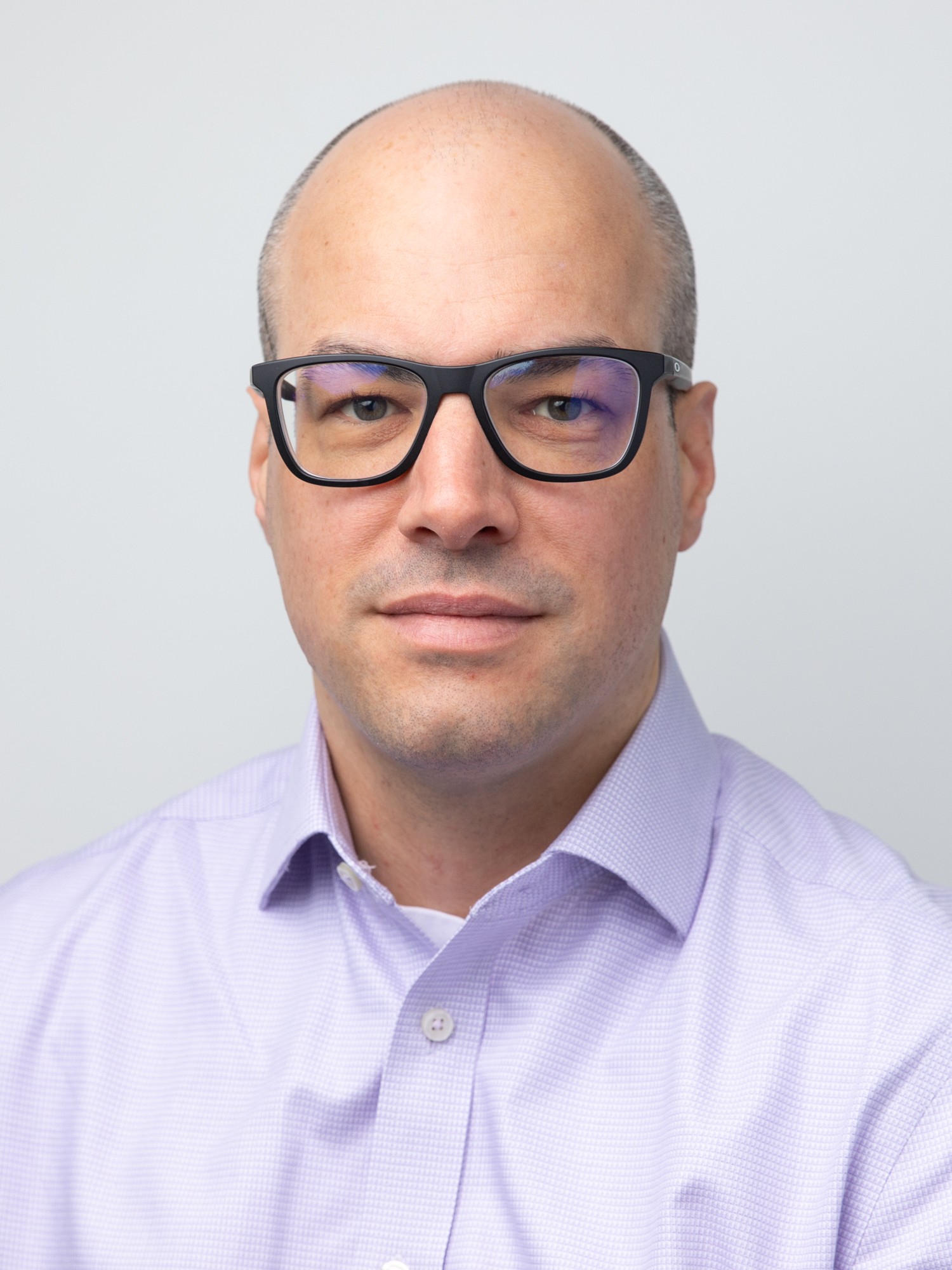Sam Keltie wearing eyeglasses and a light purple shirt.