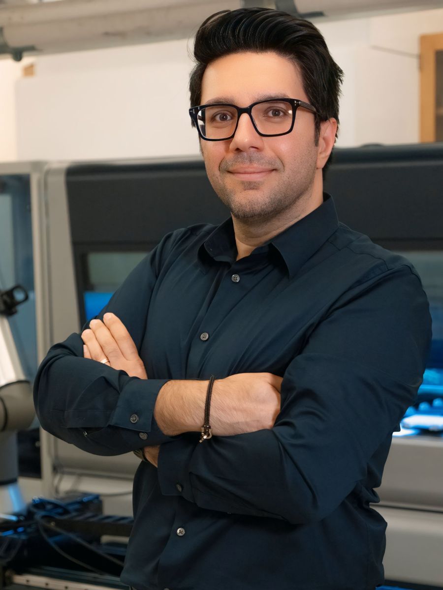 Milad Abolhasani with arms folded smiling at camera wearing black shirt and glasses