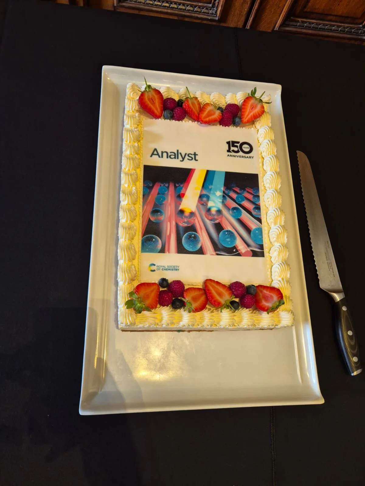 Analyst event - cake A cake topped with a icing showing a cover of a previous issue of Analyst journal, with summer fruits around the edges and a sharp knife for cutting