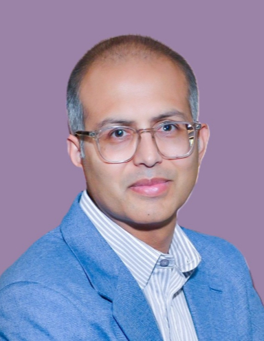 Professor Bhavik Patel wearing thin-rimmed eyeglasses, light blue shirt and blue blazer, against purple background.