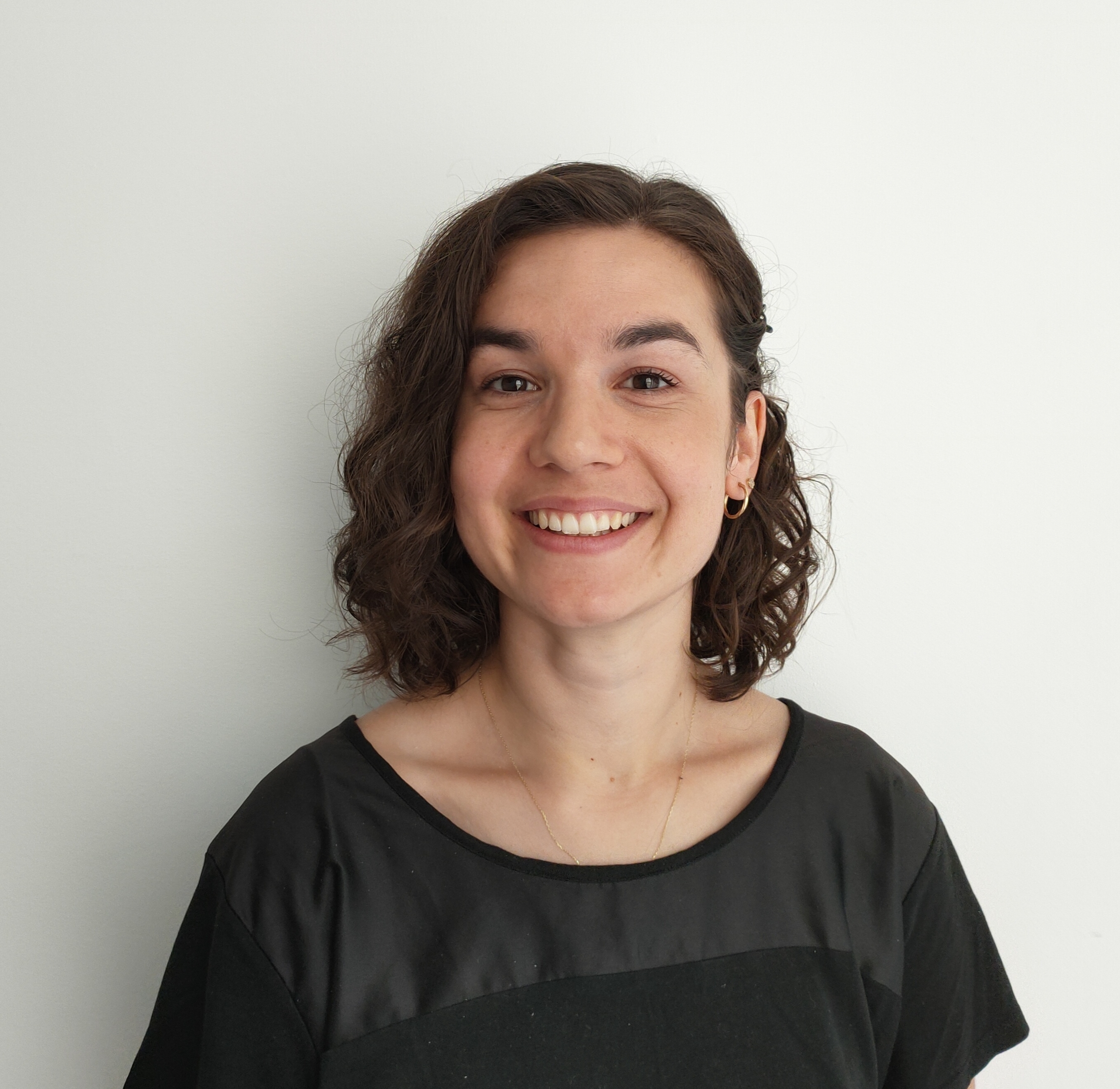 A head-and-shoulders picture of a smiling Aylin Ozkan wearing a black top and stood in front of a white background