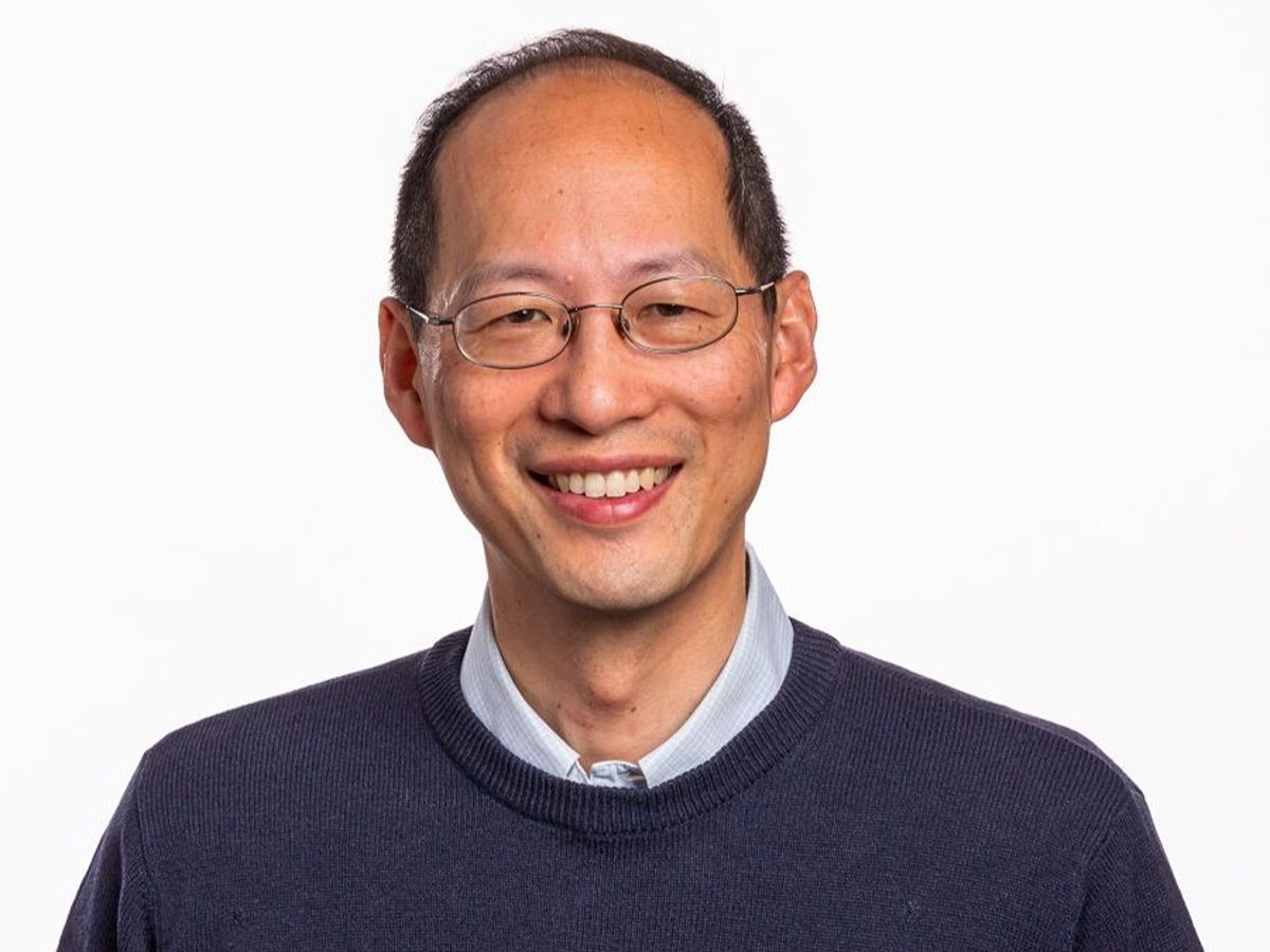  Chris Chang smiling to camera wearing glasses, shirt and navy blue jumper