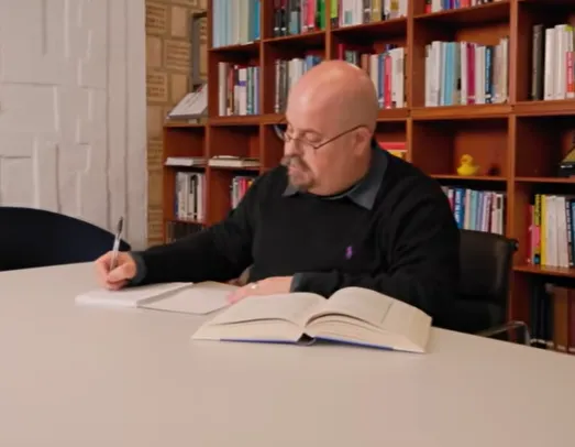 Membership hero blog - Kepa a man sitting at a table writing on a book