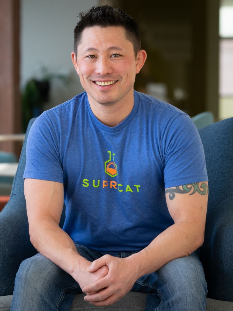Garret Miyake sitting in a chair in blue T-shirt smiling to camera