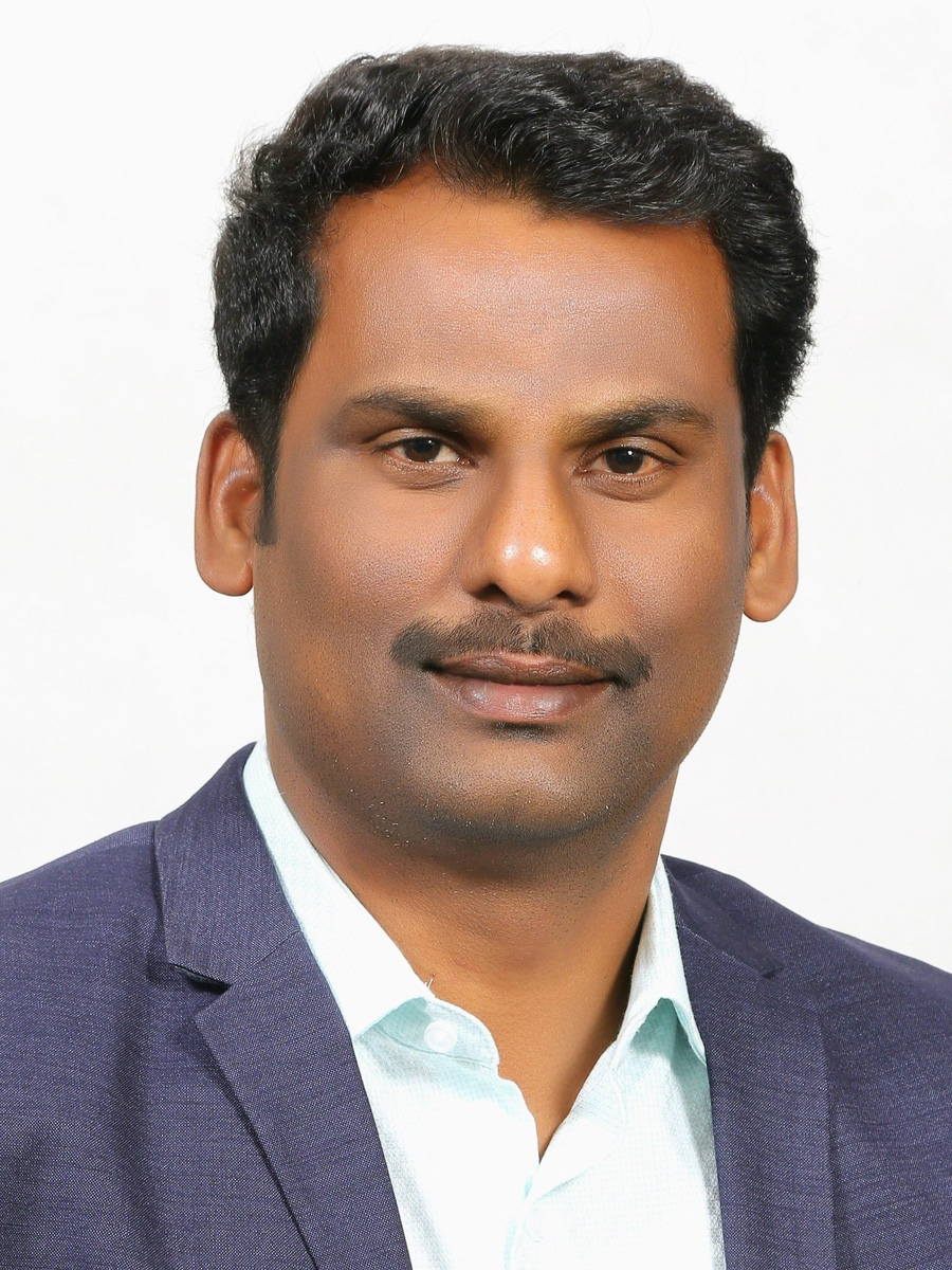 Sudarsanam Putla smiling to camera wearing navy suit jacket and white collared shirt
