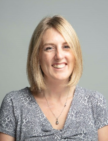 A headshot of Elizabeth Gibson, smiling, set against a plain light gray background.