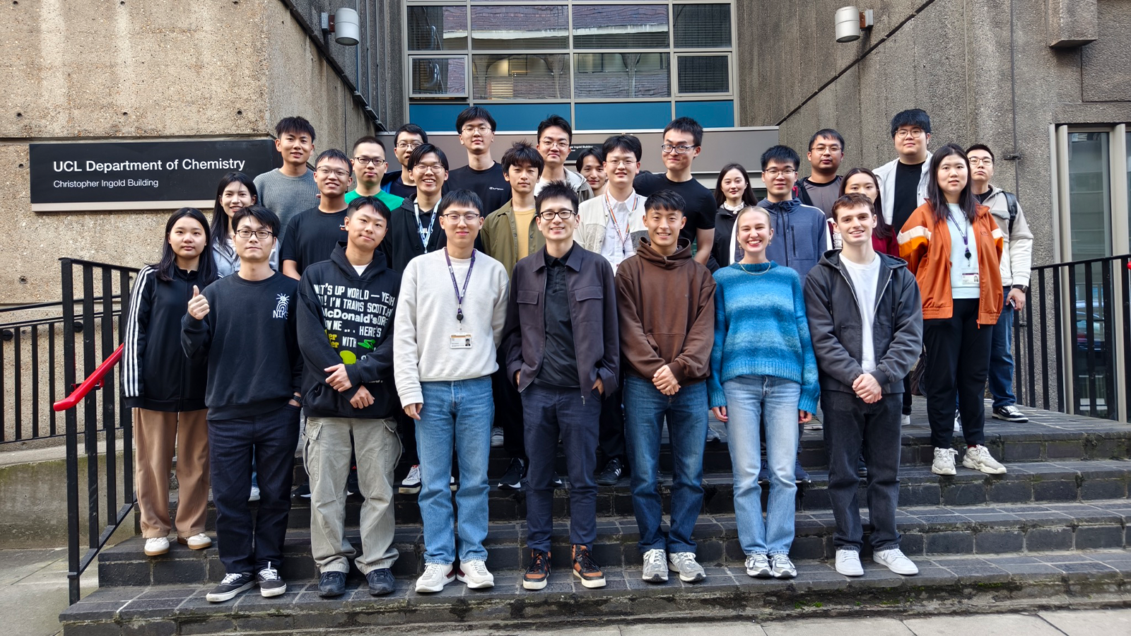 Dr Guanjie He with a group of people posing for a photo on steps outside