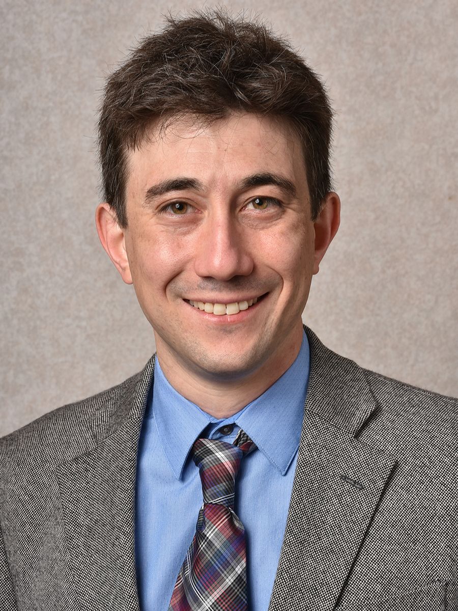 Joshua Goldberger smiling to camera in a suit and tie