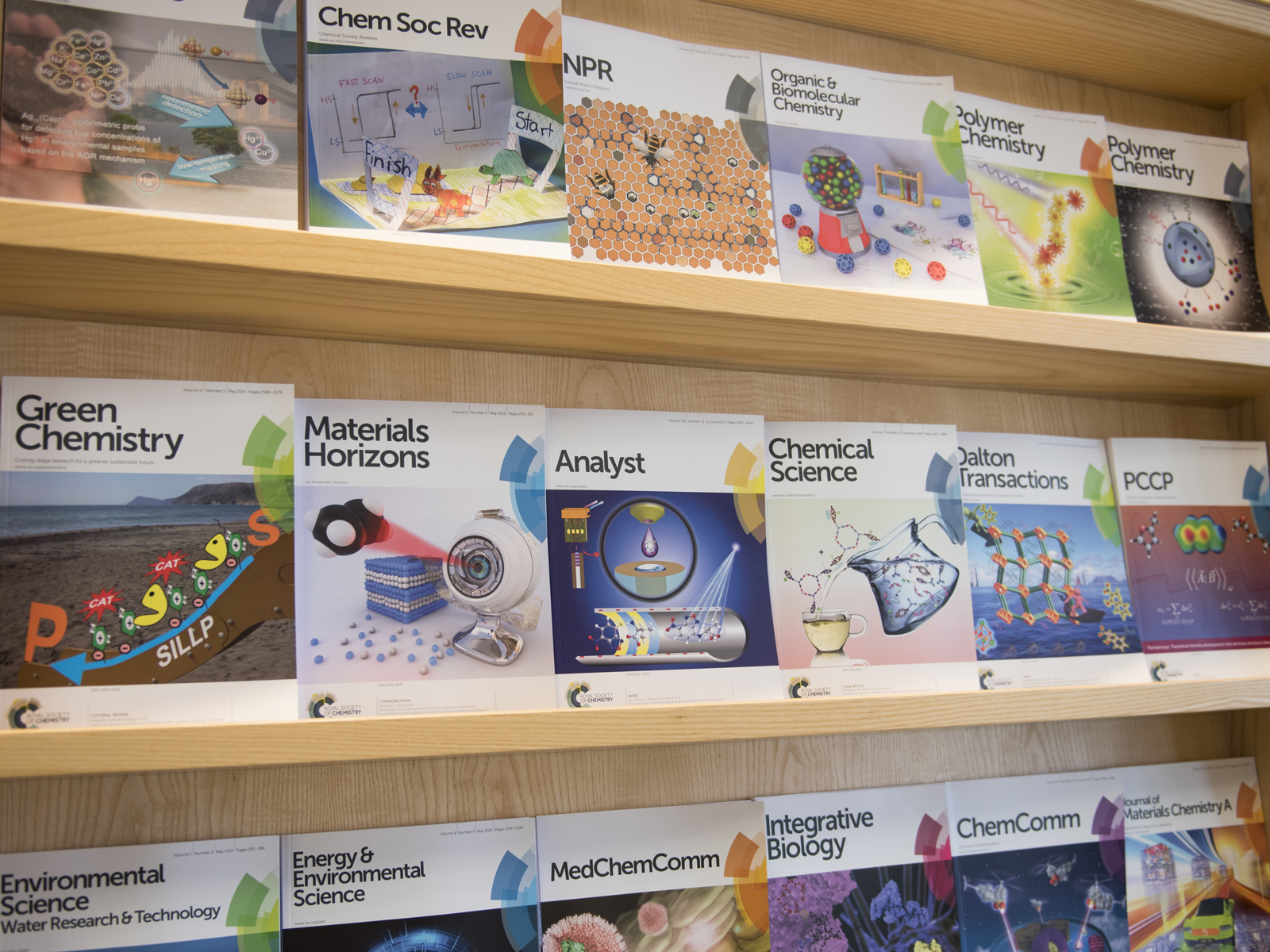 The front covers of several RSC journals on modern wooden shelves