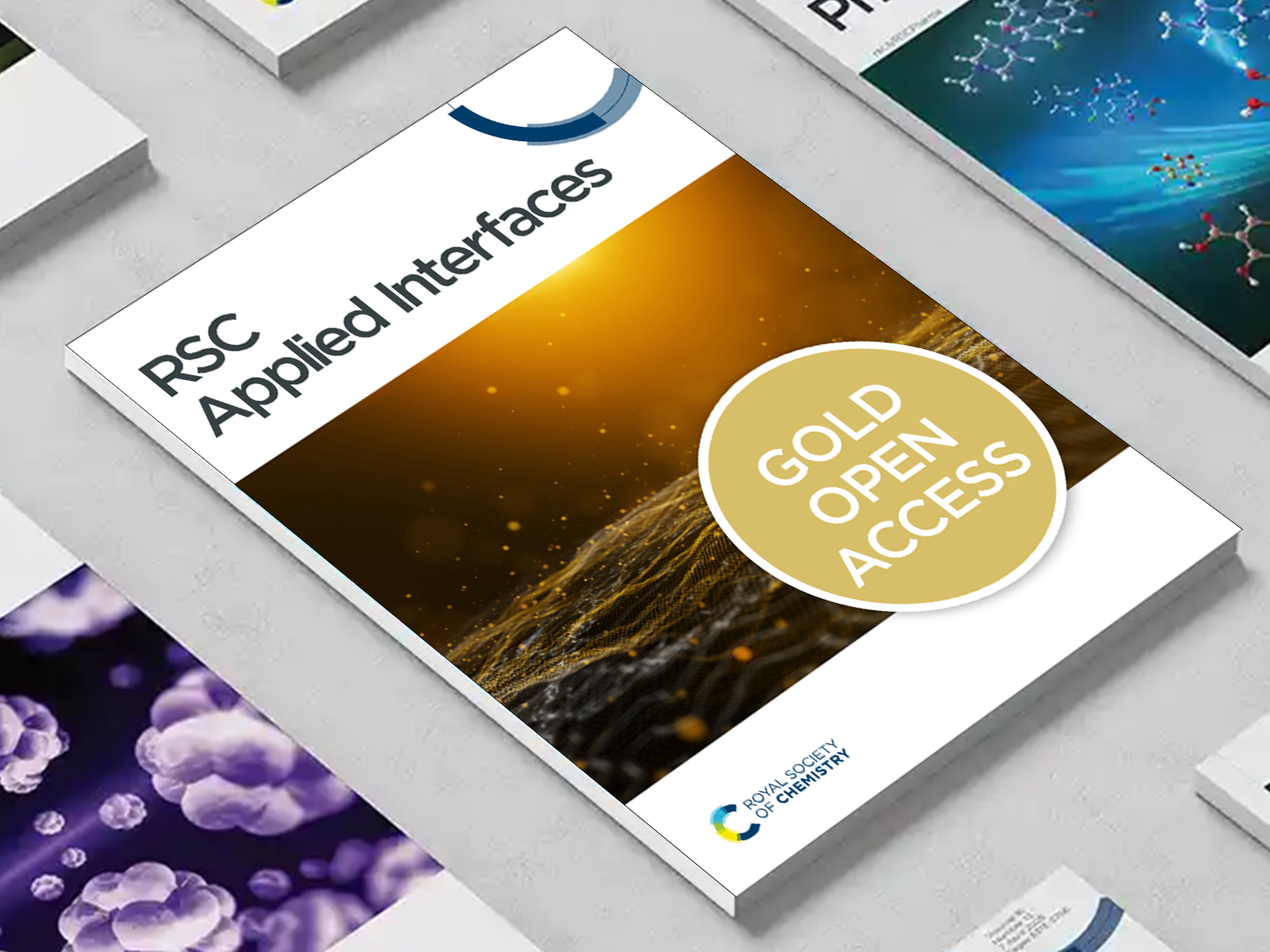 the RSC Applied Interfaces journal among a group of other journals on a desk