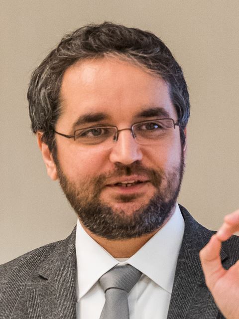 Mircea Dincă mid speech with beard and glasses