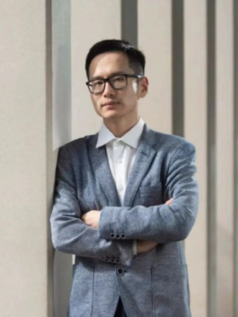 1. He - Headshot Dr Guanjie He in a suit and glasses with his arms crossed, looking at camera
