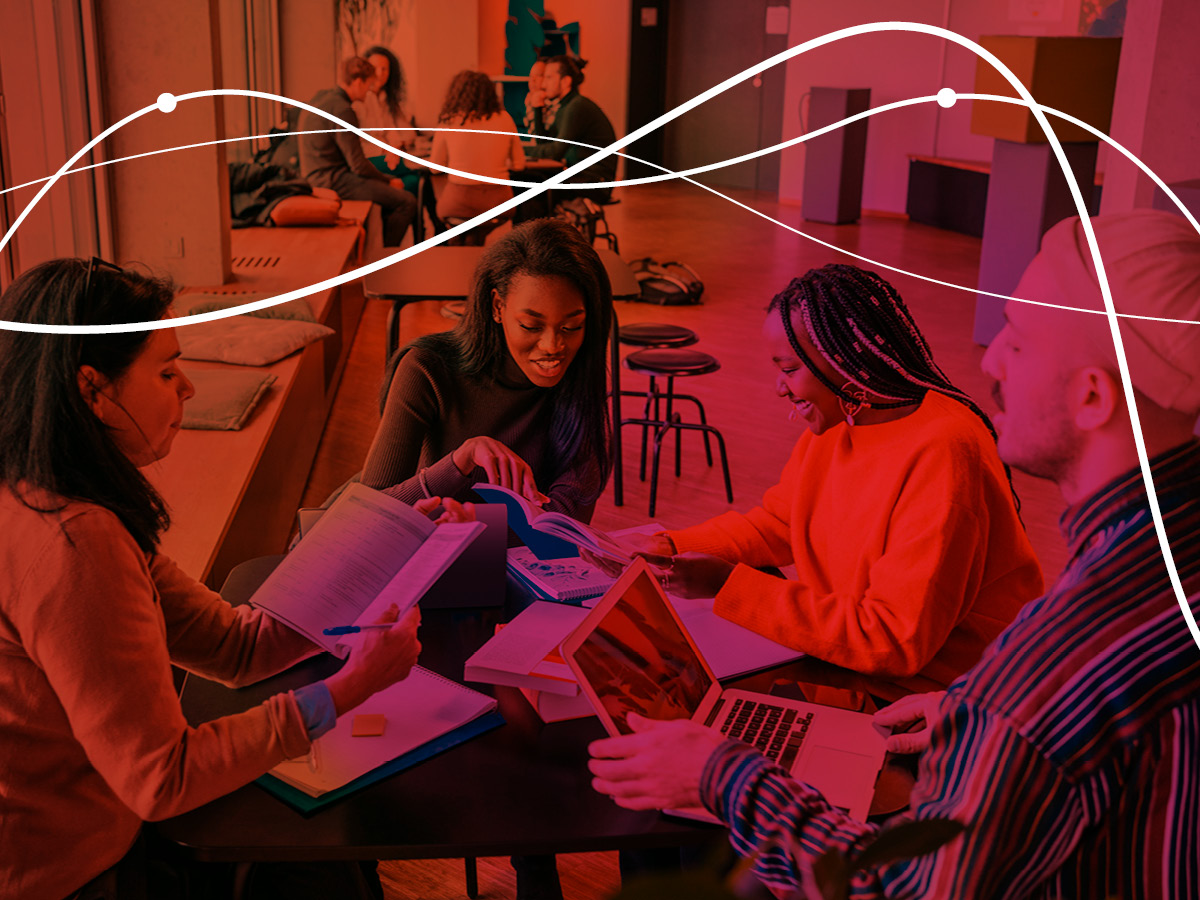 group of people talking together with laptop and books