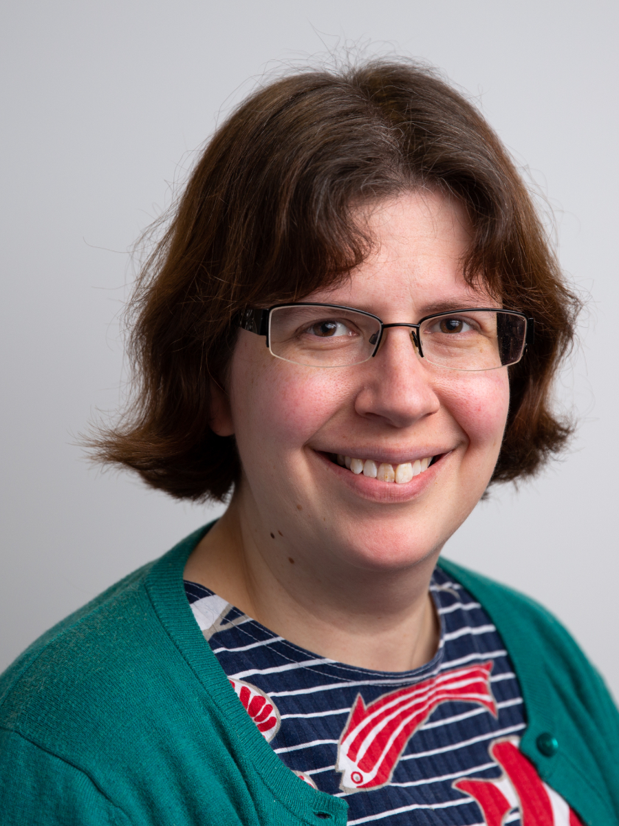 Esther Johnston wearing glasses, smiling to camera, headshot