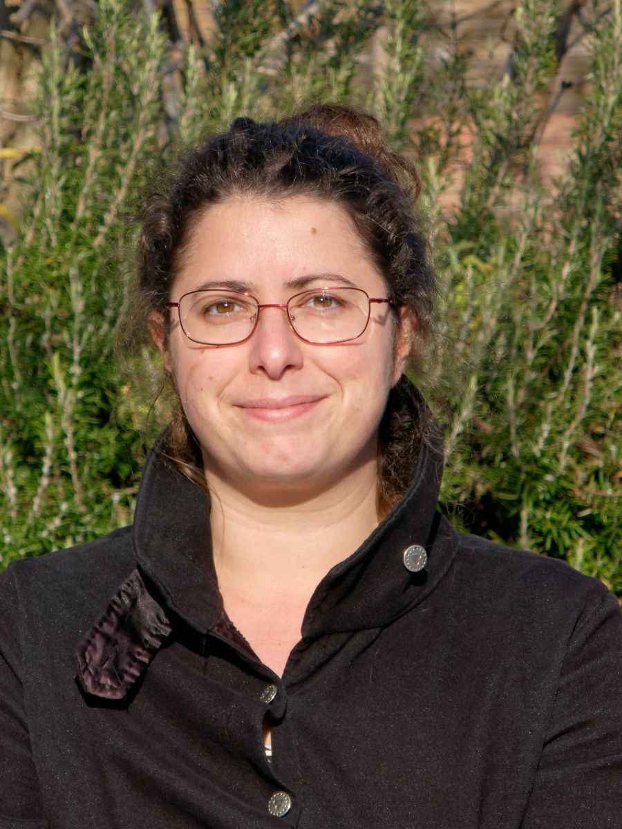 Astrid Avellan smiling to camera, wearing glasses and black jacket