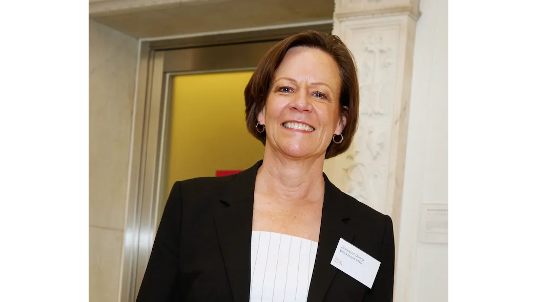 Professor Donna Blackmond in black suit jacket smiling at camera