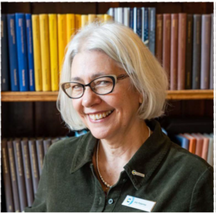 a woman smiling in front of a bookshelf