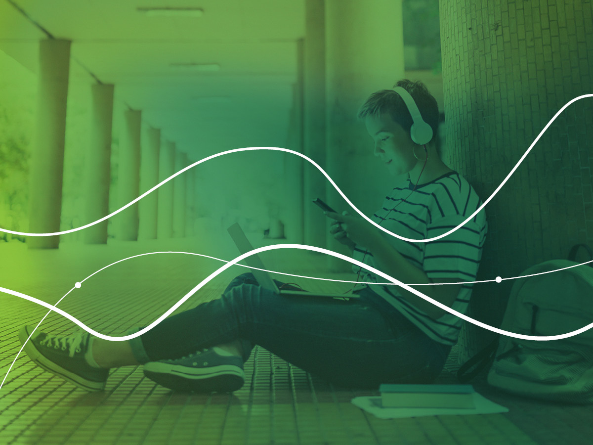 person sat on floor listening to a device using headphones