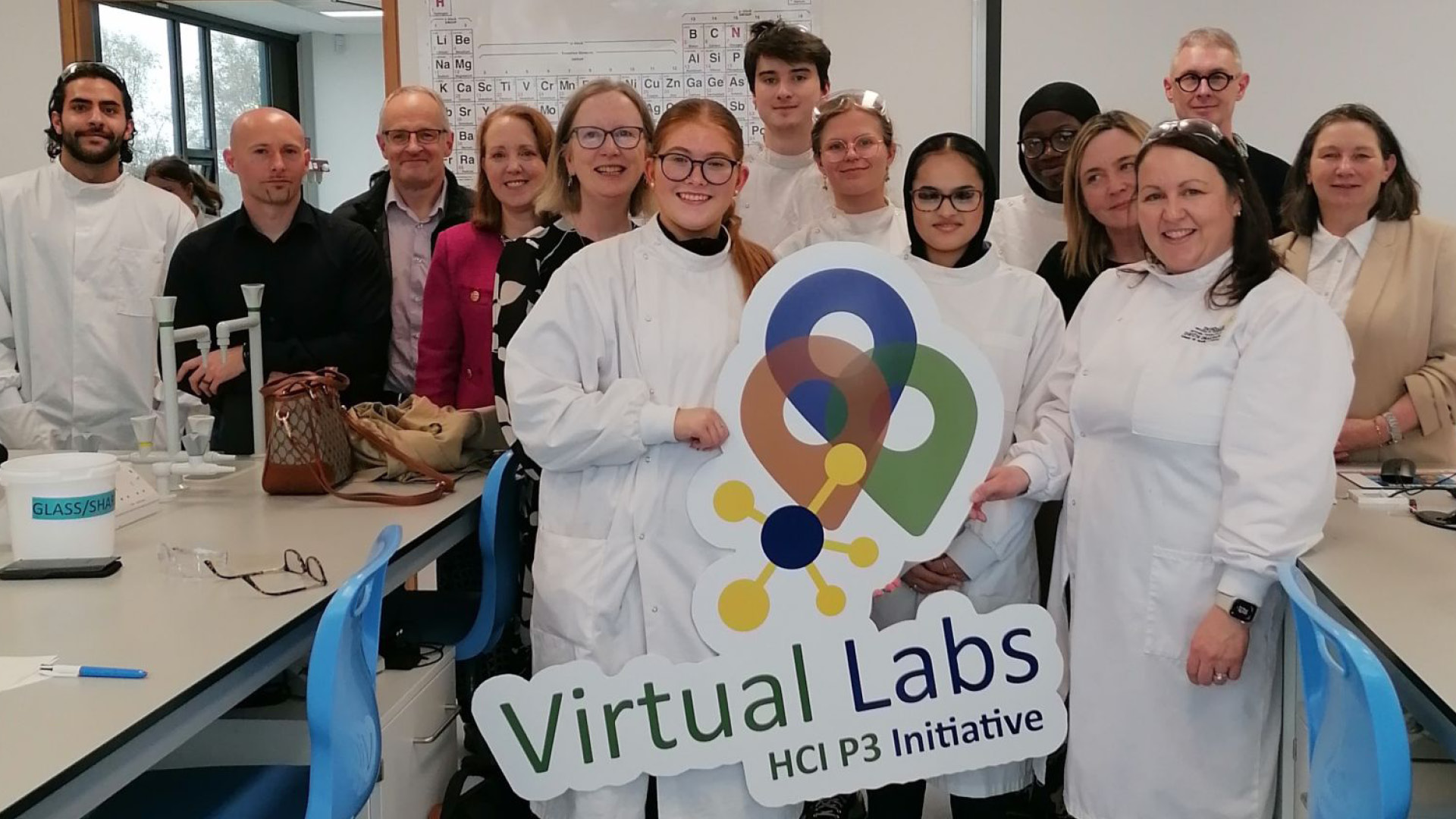 Virtual Labs Team members and students posing for photo holding large cardboard VLT logo