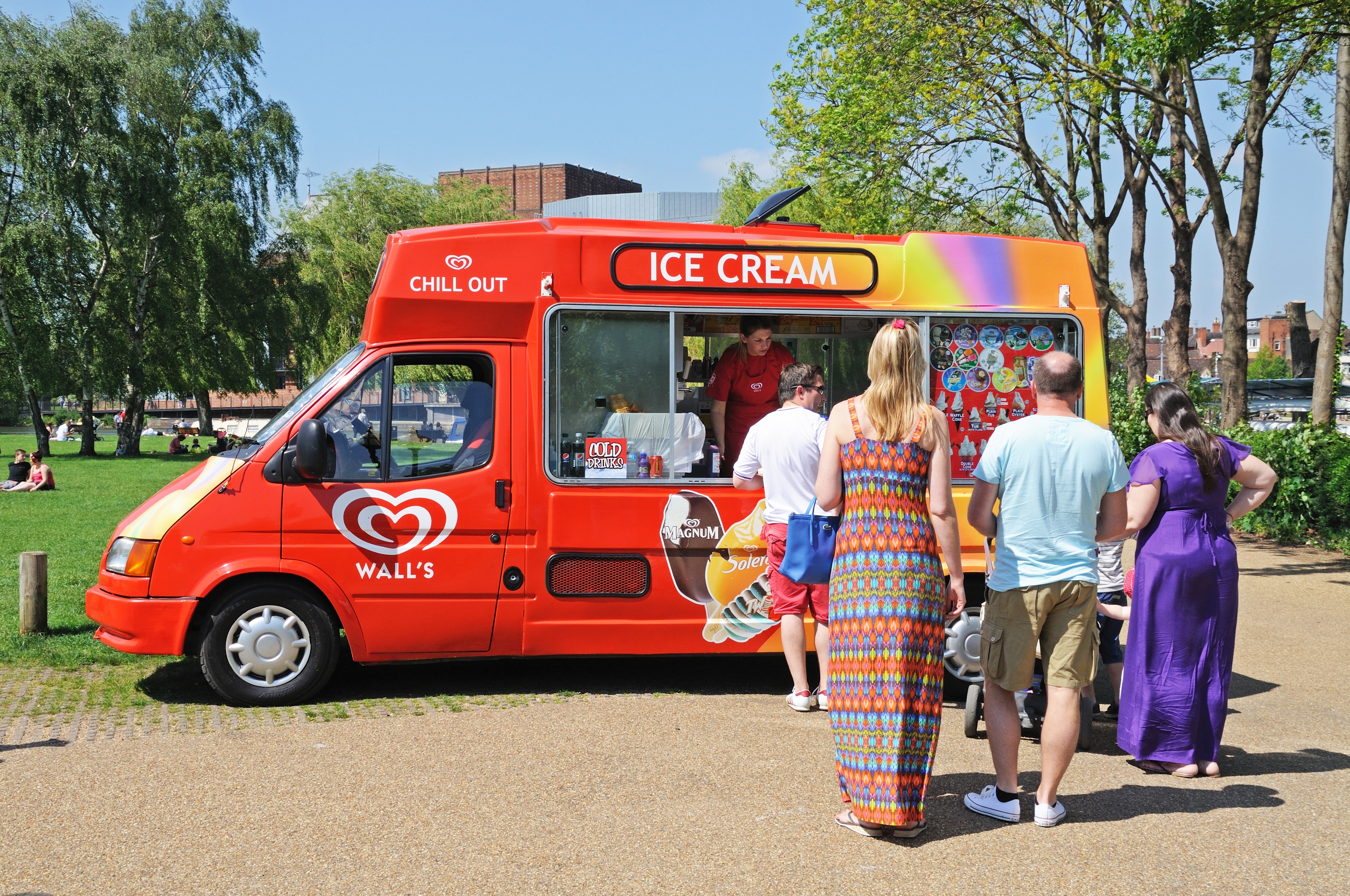 Customers queue up to buy from an ice cream van on a sunny day