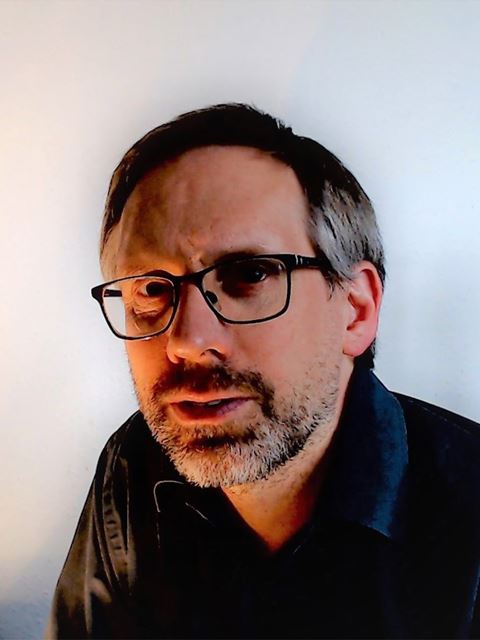 Graeme Day looking to camera with beard and glasses and black shirt