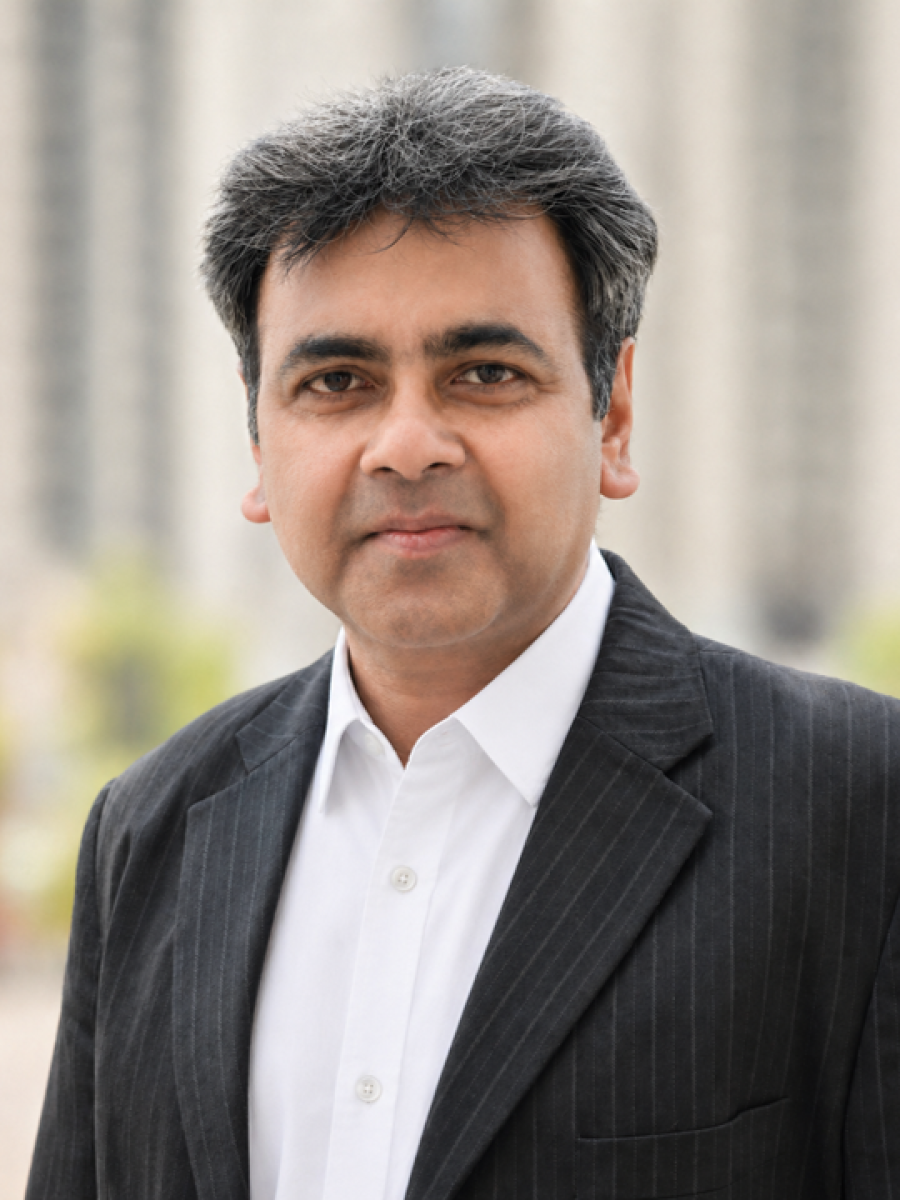 Sayan Bhattacharyya smiling in a white shirt and black blazer 