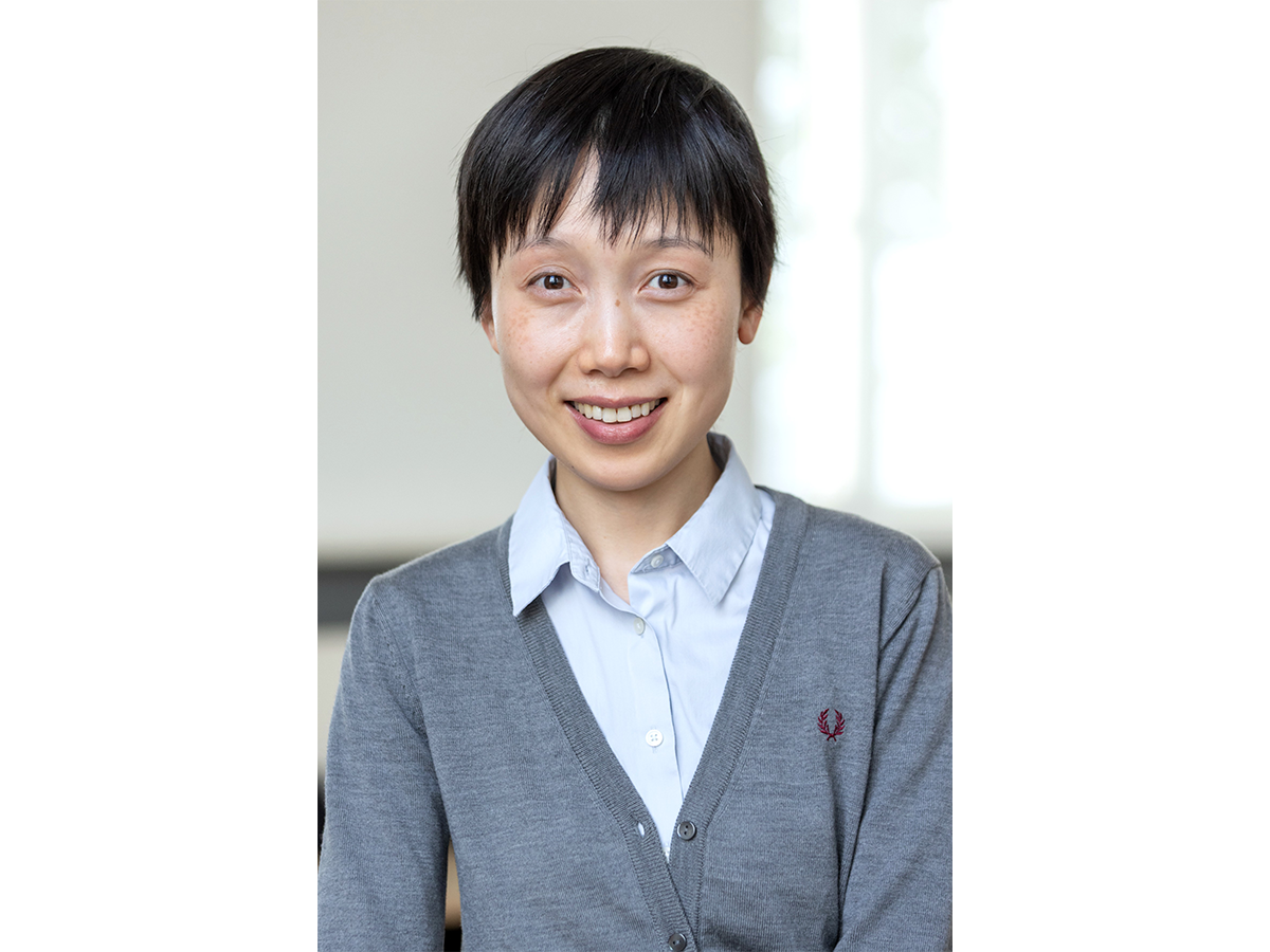 Dr Chun Ann Huang wearig pale blue shirt and grey sweater smiling at camera