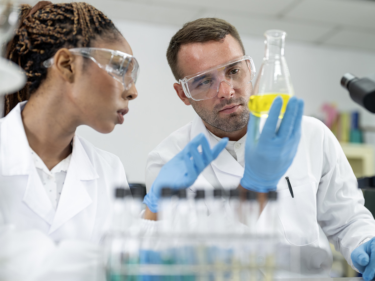 Two scientists standing in the laboratory and discussing data from experiment together