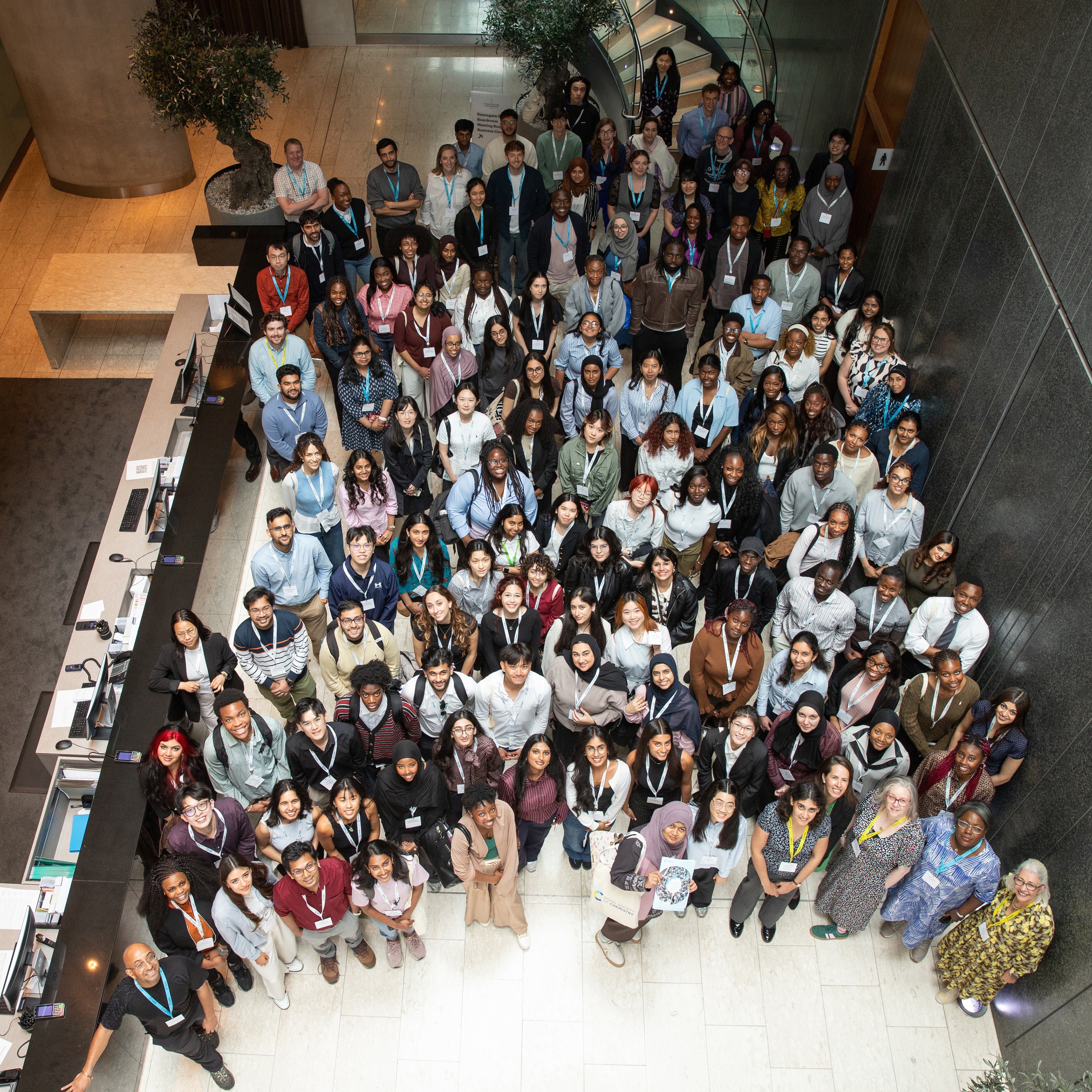 More than 100 people stand facing upward towards the camera
