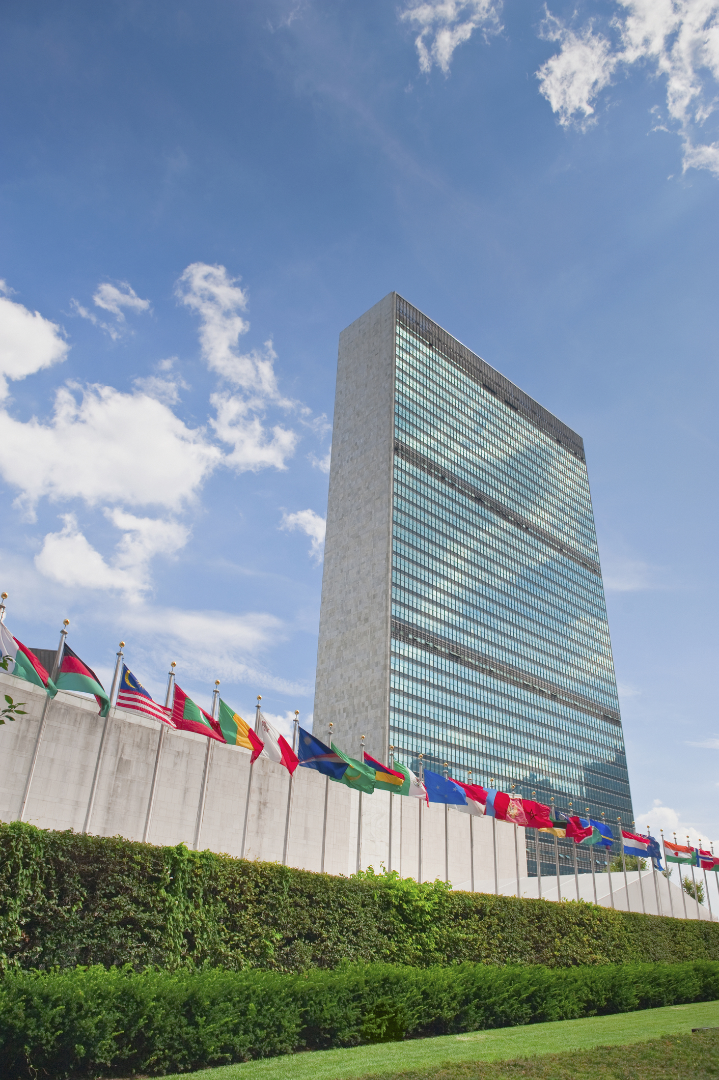 A row of flags flap in the breeze in front of the United Nations HQ building in New York