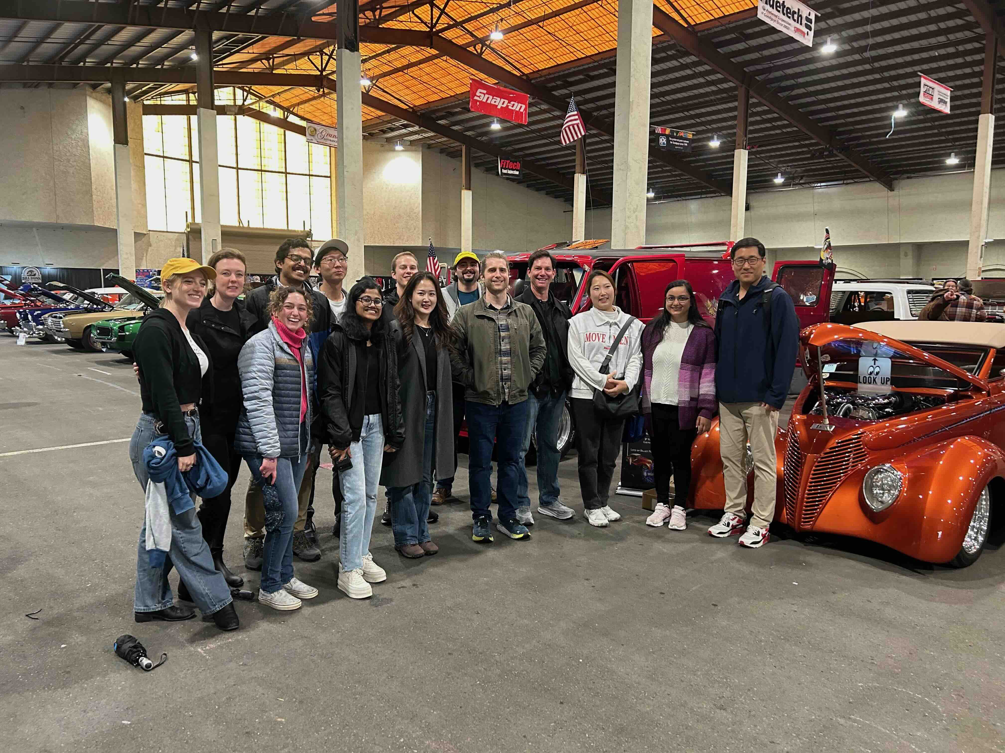 Professor Seth Cohen and otehrs in front of racing cars at an event