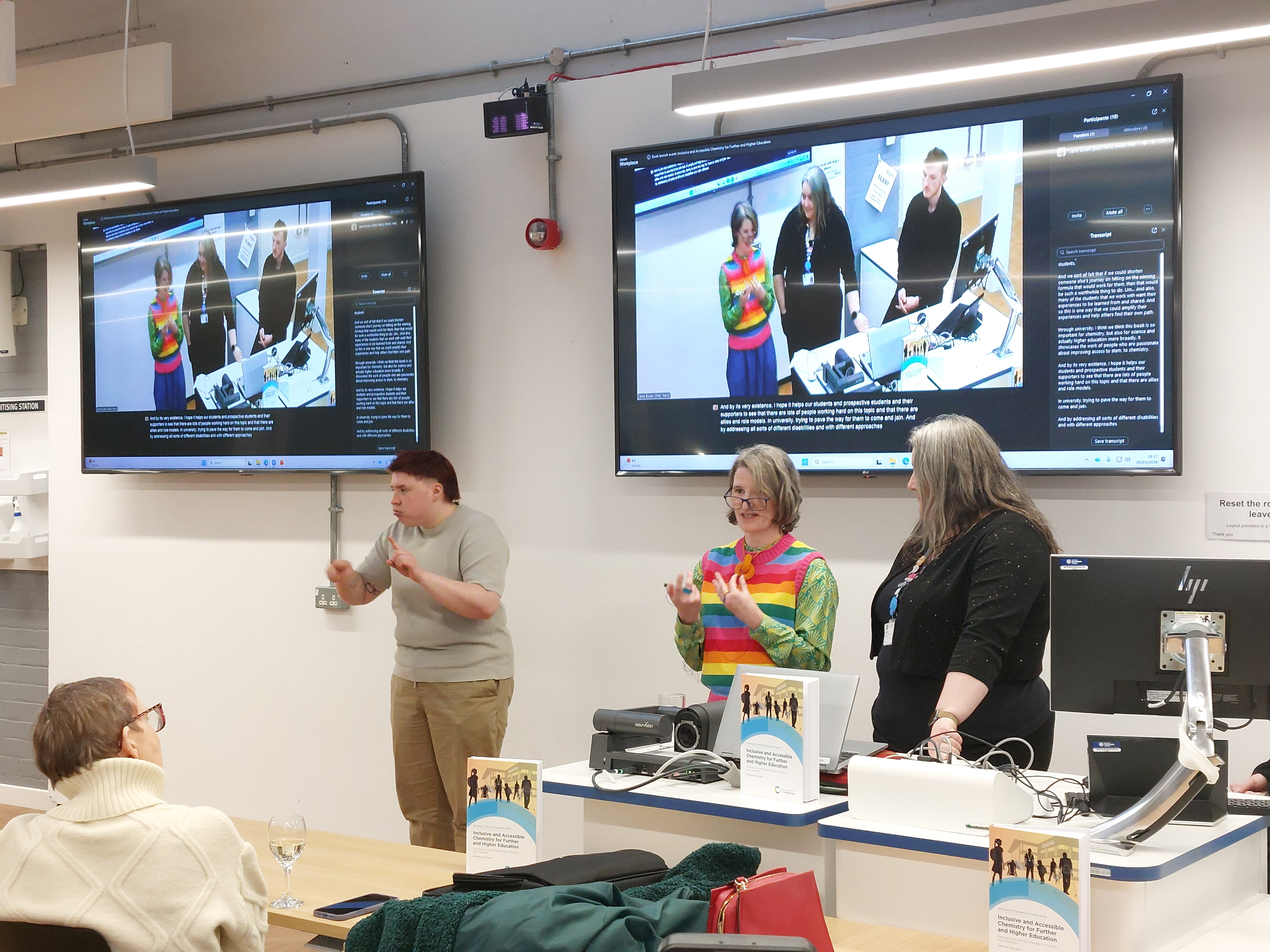 Dr Jean O'Donoghue and Dr Kirsty Ross (centre and right) present towards the group, while a BSL interpreter signs the presentation for deaf attendees