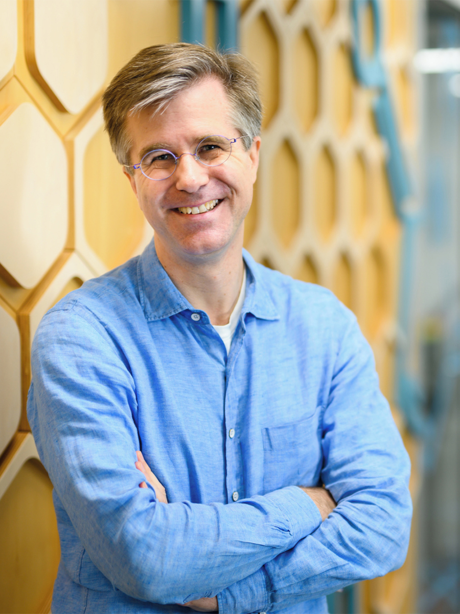 Christopher Barner-Kowollik smiling to camera wearing glasses and blue shirt