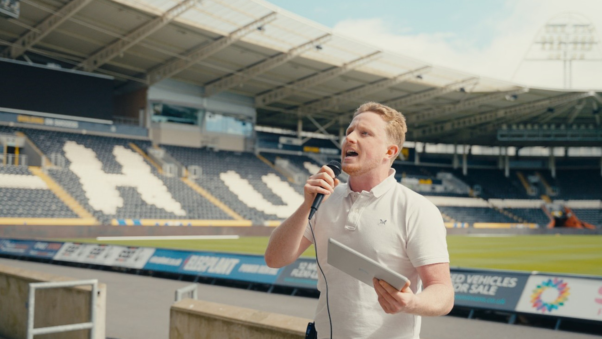 Liam Johnson talking to a big group of children about science in a football stand